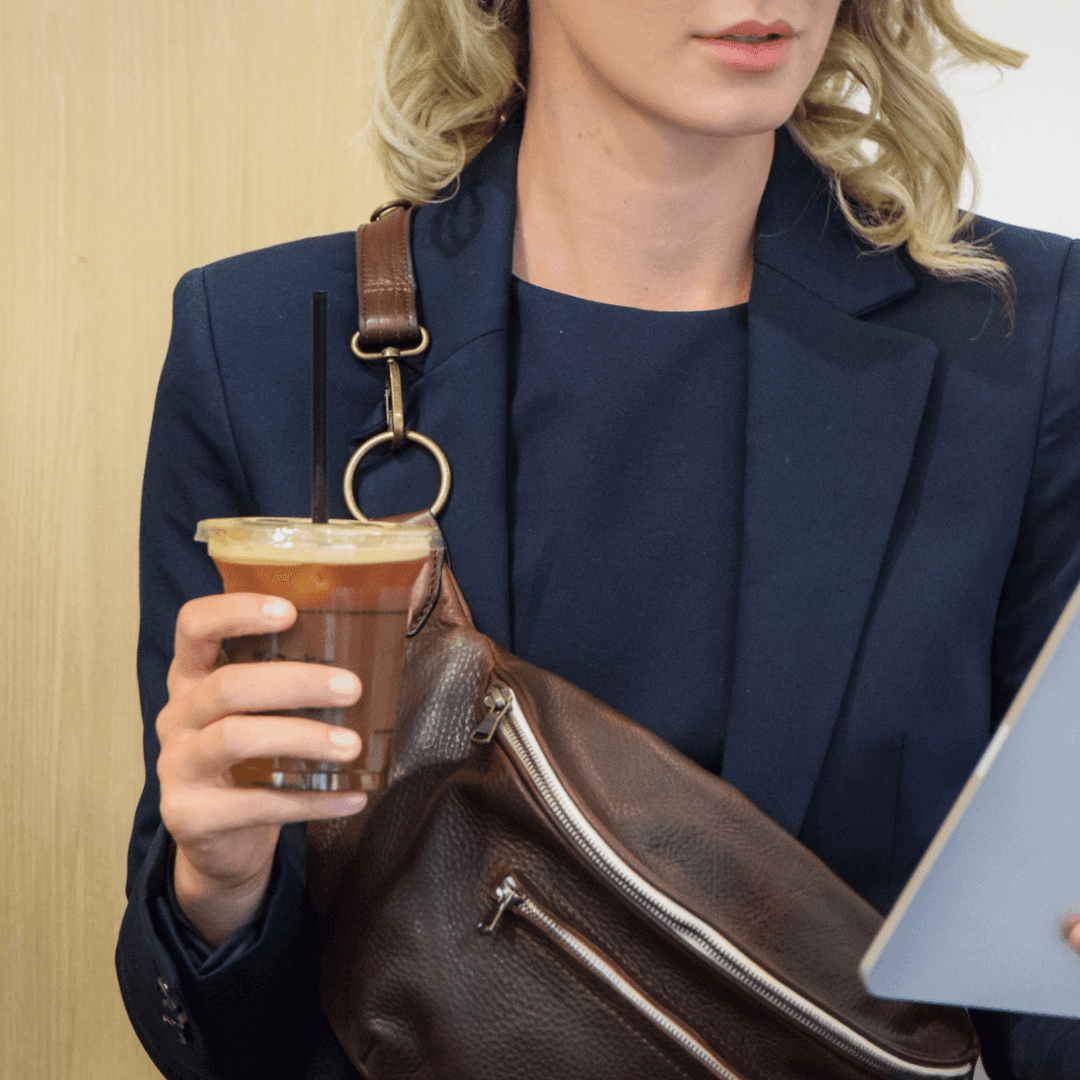 Model wearing the Zendira Saturday concealed carry crossbody in Coco Creme at a cafe
