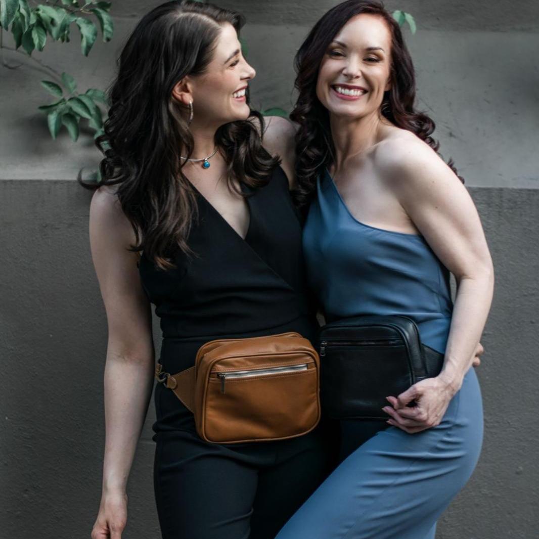 Two individuals smiling and posing with concealed carry pouches attached to their belts