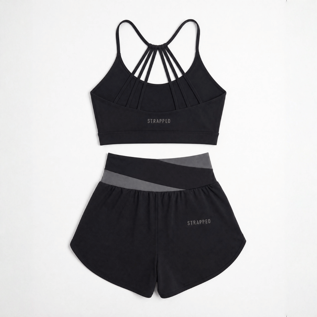 Black Strapped by Zendira sports bra and athletic shorts set displayed on a white background.