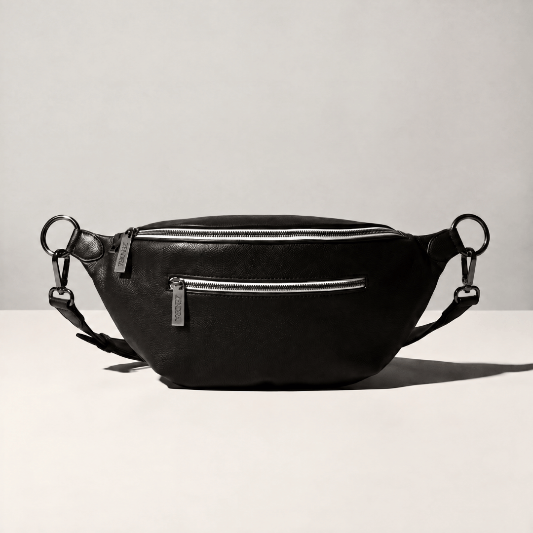 A black leather ZENDIRA bag with silver zippers and hardware, displayed on a light gray surface against a neutral background.